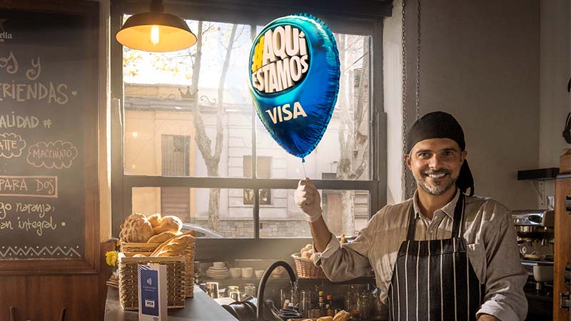 Panadero sosteniendo el globo de Visa #AquíEstamos
