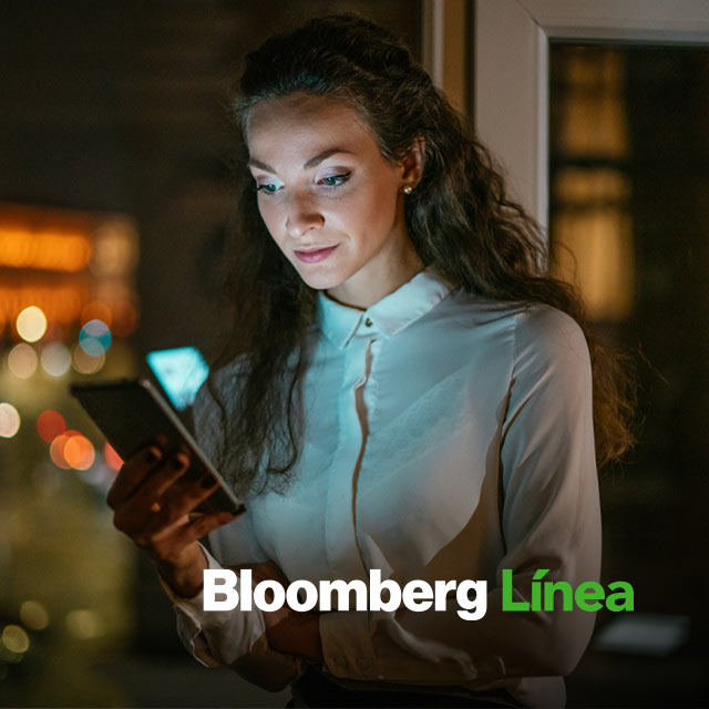 Mujer usando su celular con logo Bloomberg Línea